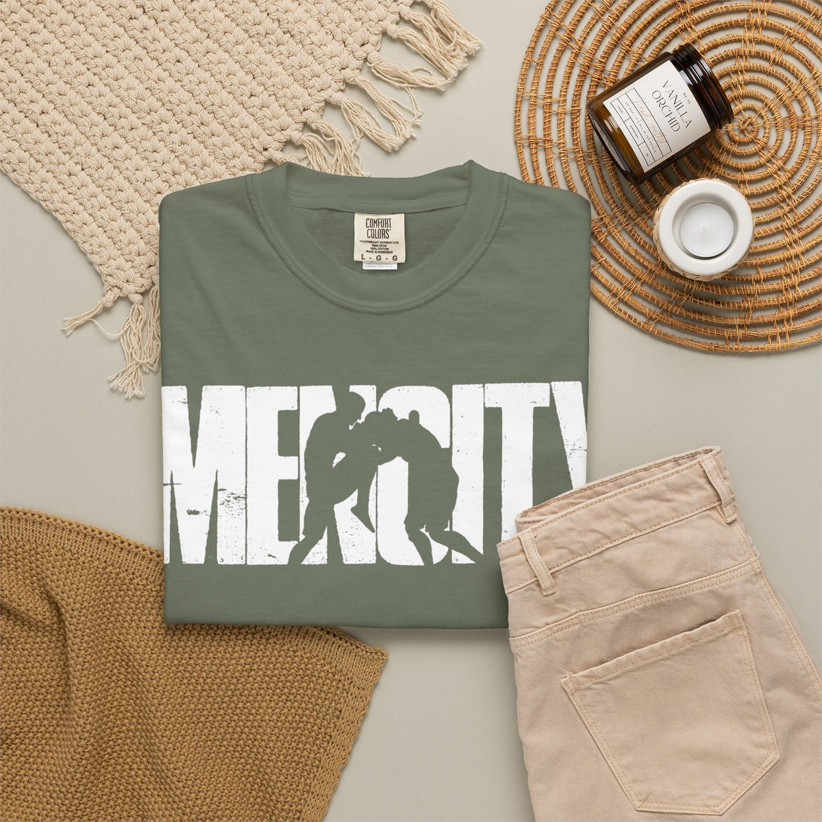 Moss green Mencity Fighter gym t-shirt folded in a flat lay with beige trousers and a candle