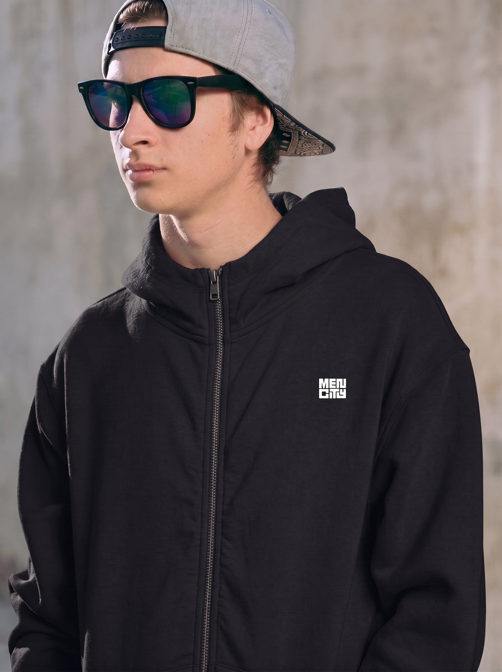 Man wearing the black Mencity essential zip hoodie with hood up and small chest logo, close-up
